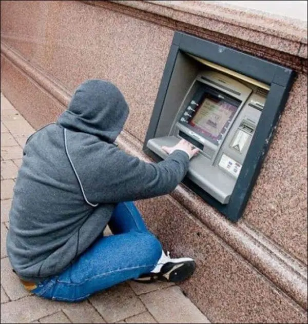 man sitting down using low down atm 