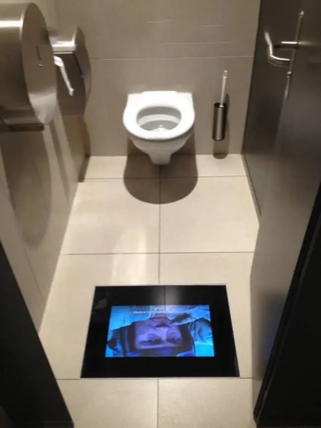 toilet with tv screen on the floor showing movie