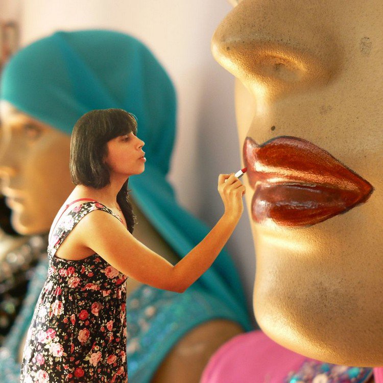 tiny woman painting mannequin lips