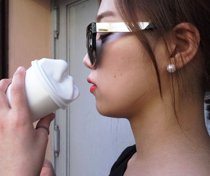 girl holding face coffee cup