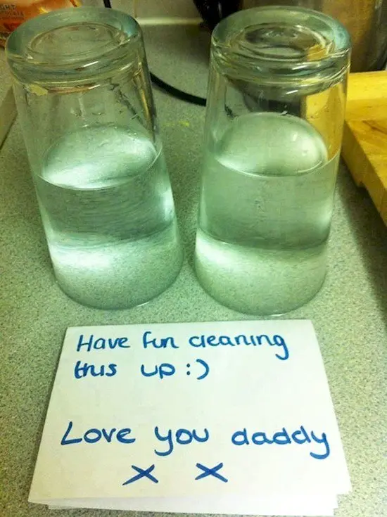glasses upside down filled with water beside note saying have fun cleaning this up