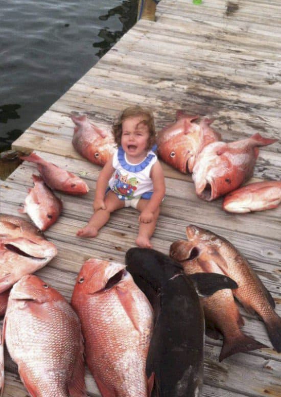 kid surrounded by dead fish