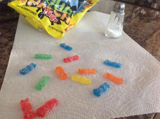 sour patch kids candies covered in salt next to salt shaker
