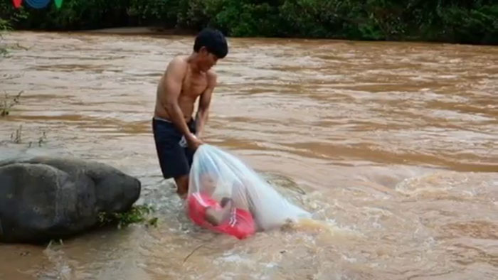 man dragging kid in plastic bag cross river