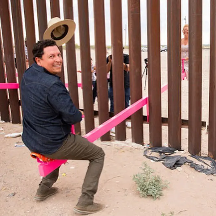 adult playing seesaw in the us mexican border