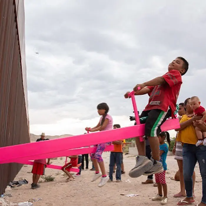child in red seesaw in the us mexican border
