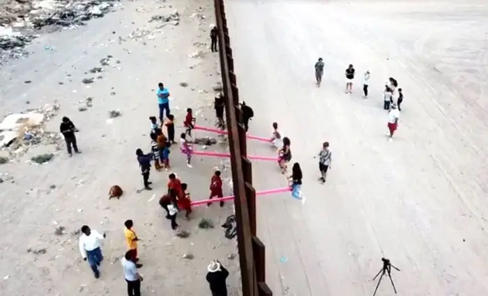 happy people playing seesaw in the us mexican border