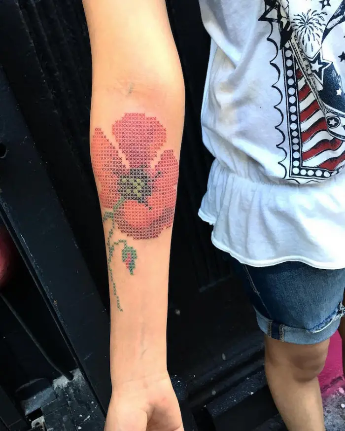 lower arm with cross stitched flower best floral tattoo artists