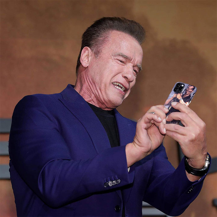 Arnold Schwarzenegger Holding an iPhone 11 Pro with an Arnold Schwarzenegger Rocket Launcher Case