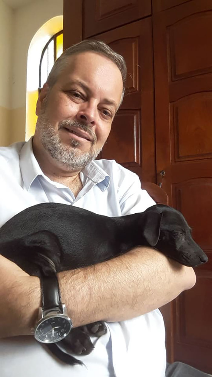 Father João Paulo Araujo Gomes Carrying a Black Stray Dog