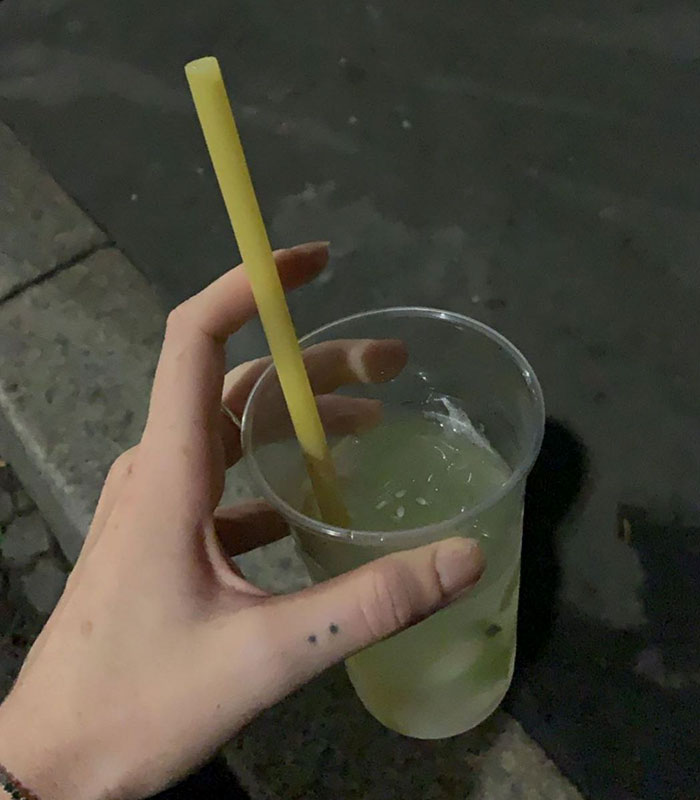 Hand Holding a Cup of Cucumber Lemonade with Pasta Straw