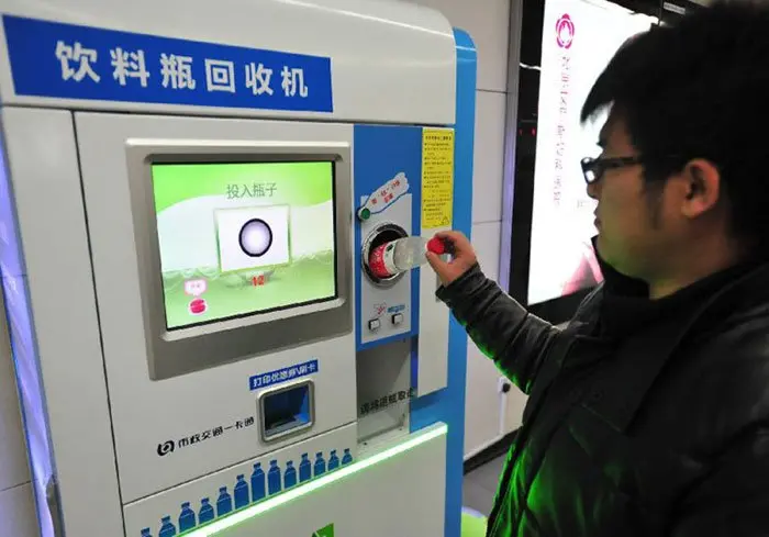 Man Inserting a Plastic Bottle to a Payment Terminal at Beijing Subway