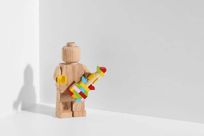 LEGO Wooden Figure Holding a Colorful LEGO Tower with Its Left Hand