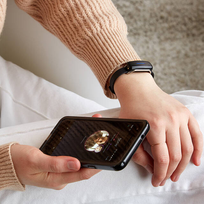 Woman's Hand Wearing a Vibrating Bracelet and Holding a Phone