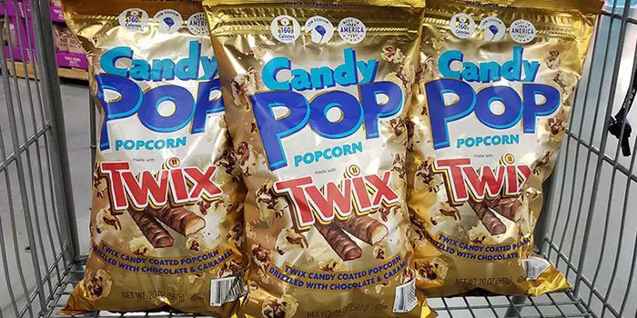 three bags of twix popcorn in a shopping cart