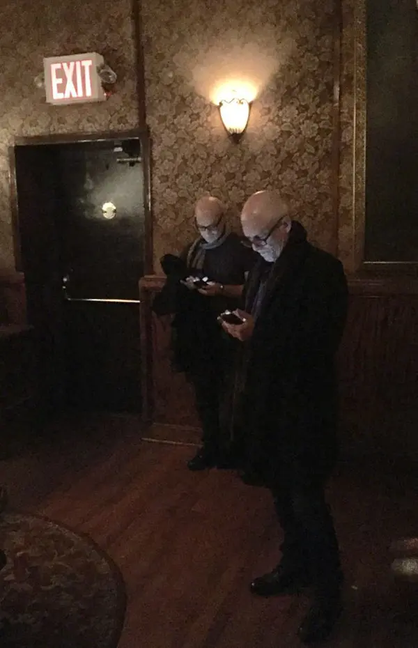 bald guys with eyeglasses checking out phone