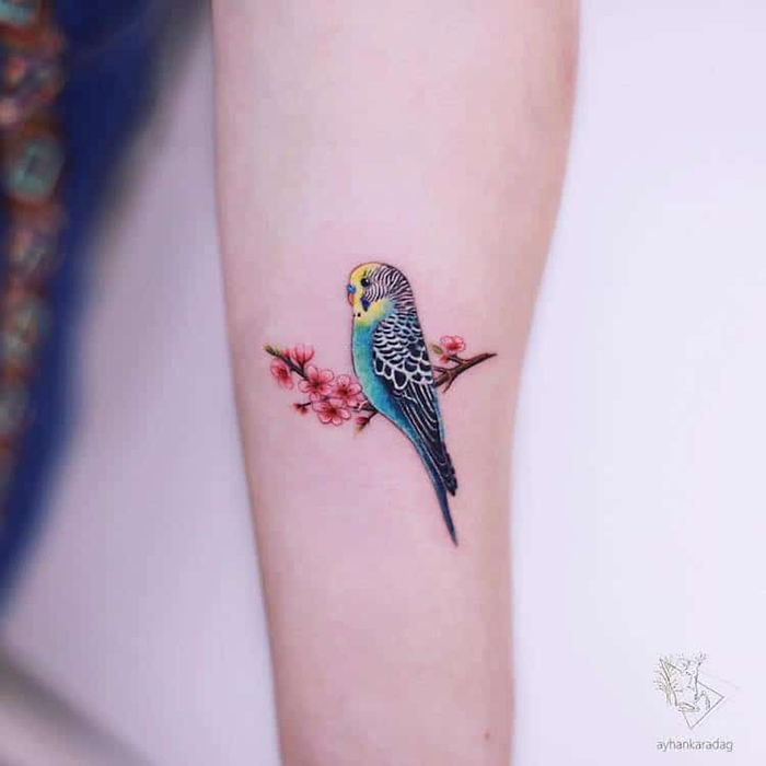 cute tattoos colorful bird sits atop a cherry branch