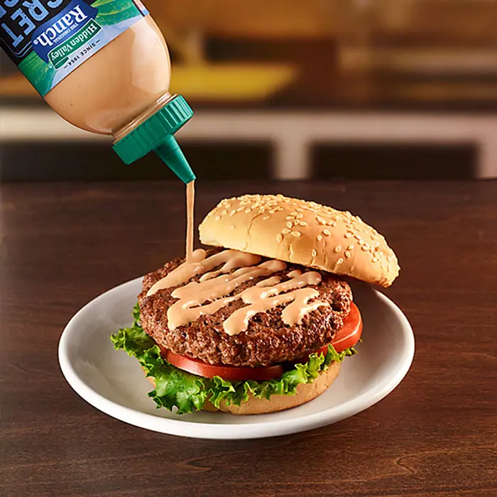 secret sauce being used on a burger