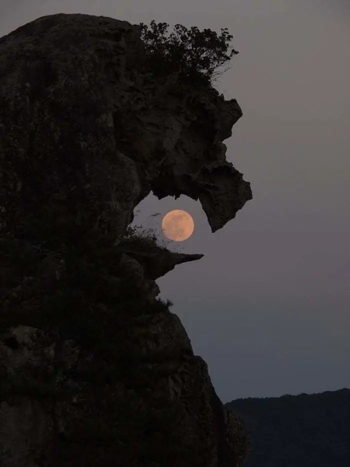 rock formation looks like it's swallowing the moon