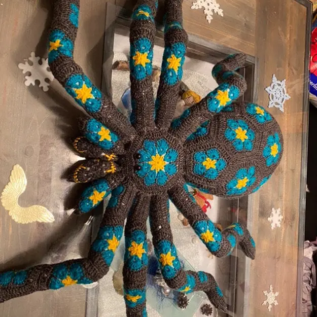 dark gray crochet spider with yellow and blue flower deails