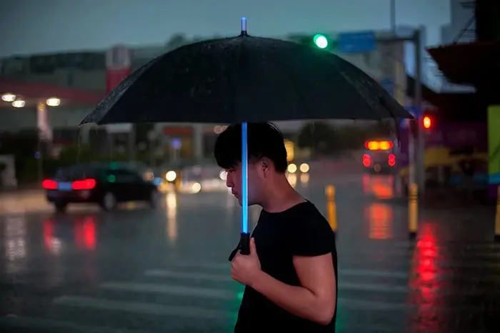 man holding blue lightsaber umbrella