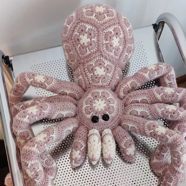 pink giant crochet spider on a metal chair