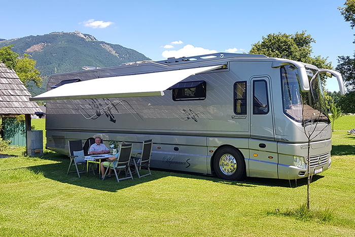 parked luxury motorhome with awning and outdoor dining setup