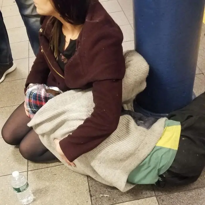 woman comforts homeless man in subway
