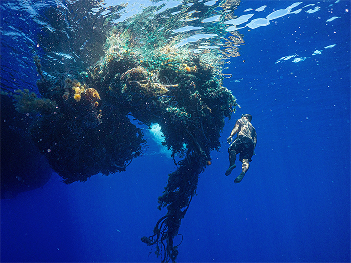 diver next to a large mass of ocean plastic