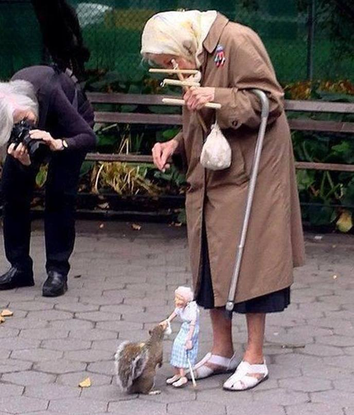 old woman using marionette to feed squirrels