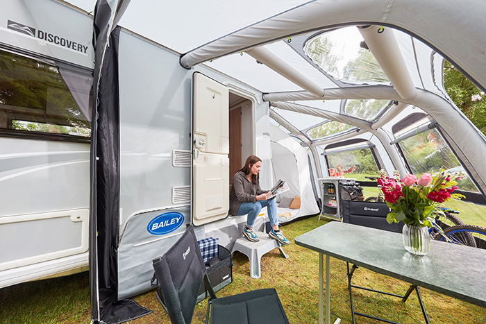 lady reading a magazine and sitting by the entrance of an rv