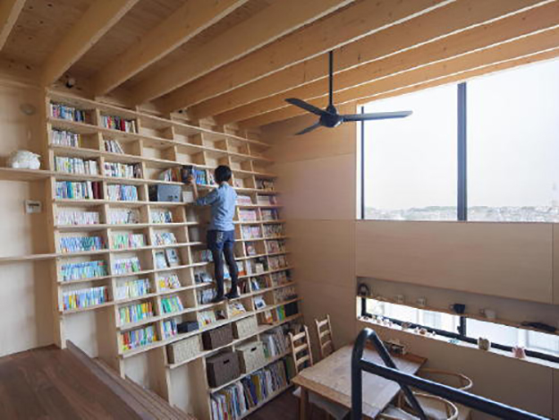 Shin Yoshida stands on his earthquake-proof bookshelf