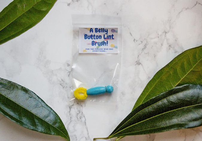 belly button lint brush with sky blue handle and yellow bristles