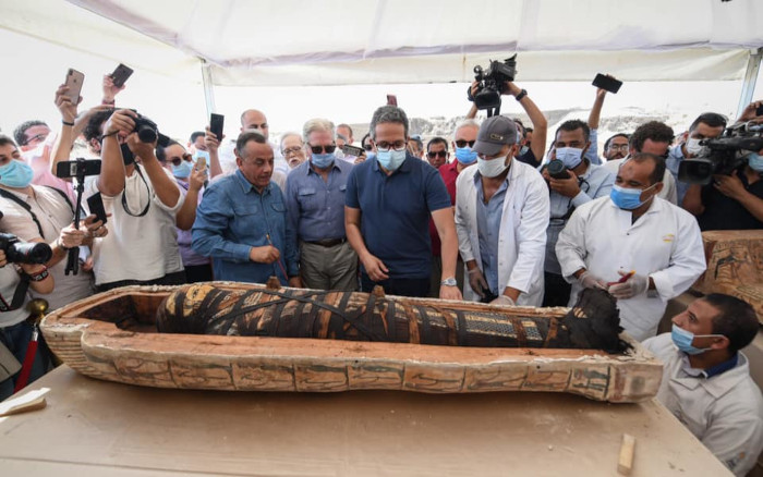 members of the ministry of tourism and antiquities media and dignitaries crowd around the opened Egyptian coffin