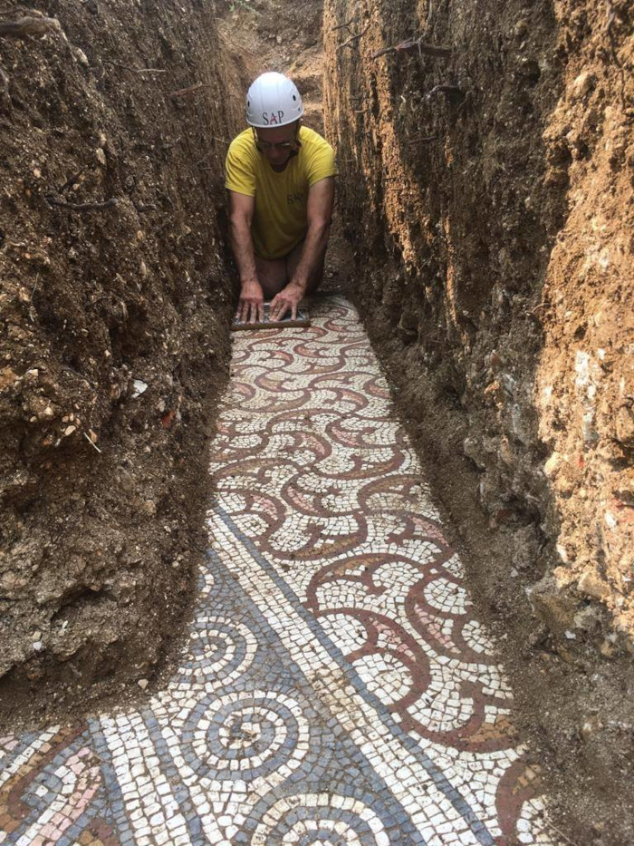 an archaeologist carefully removes the soil from the ancient roman mosaic floor