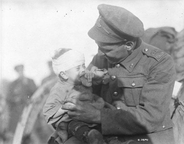 canadian soldier comforts a crying belgian baby