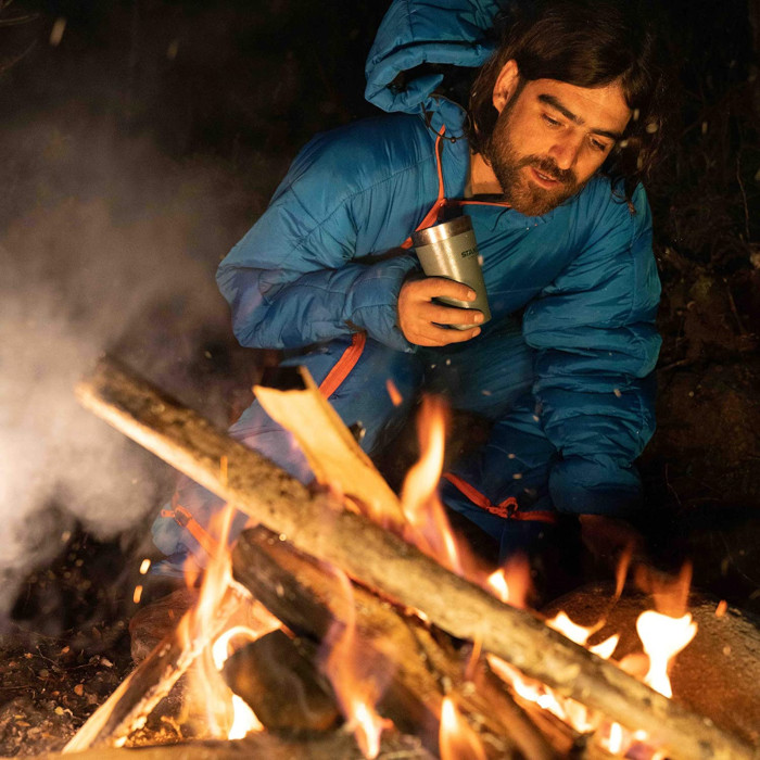 male camper wears blue sleeping bag onesie