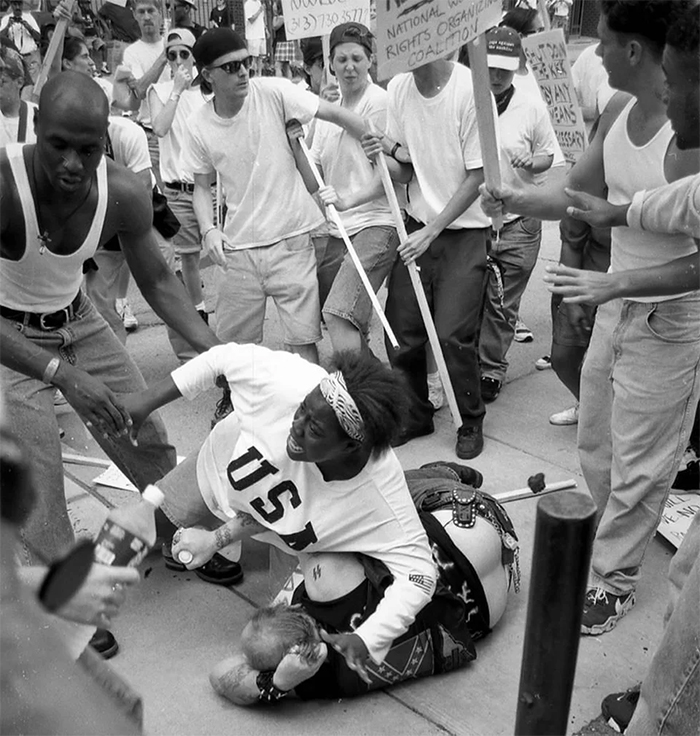 young woman protects man from angry mob