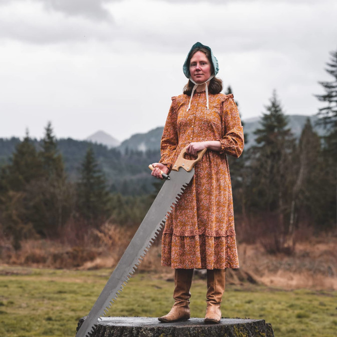 Lady wearing orange dress stands atop a tree stump to participate in Target dress roasting