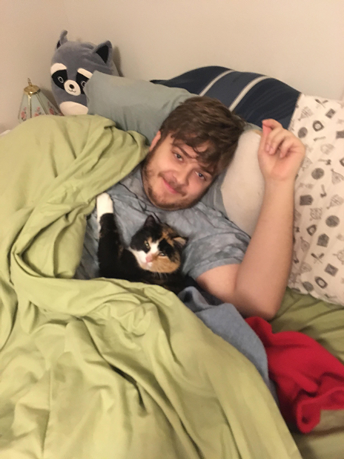 cat clinging on to owner's boyfriend on bed