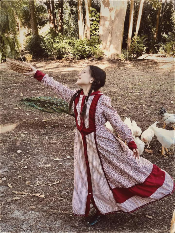 little girl gracefully poses in red prairie dress