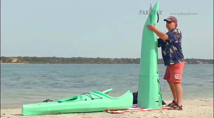 man assembling pakayak portable kayak by the shore