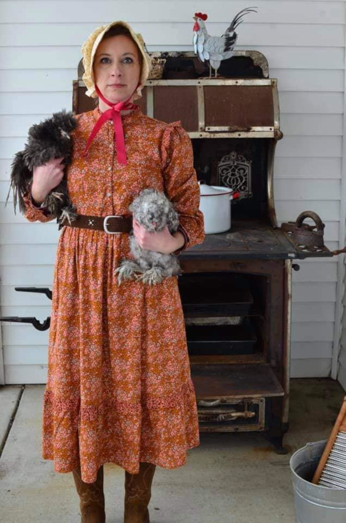 woman wins the target dress roasting event by posing with chickens and an ancient stove