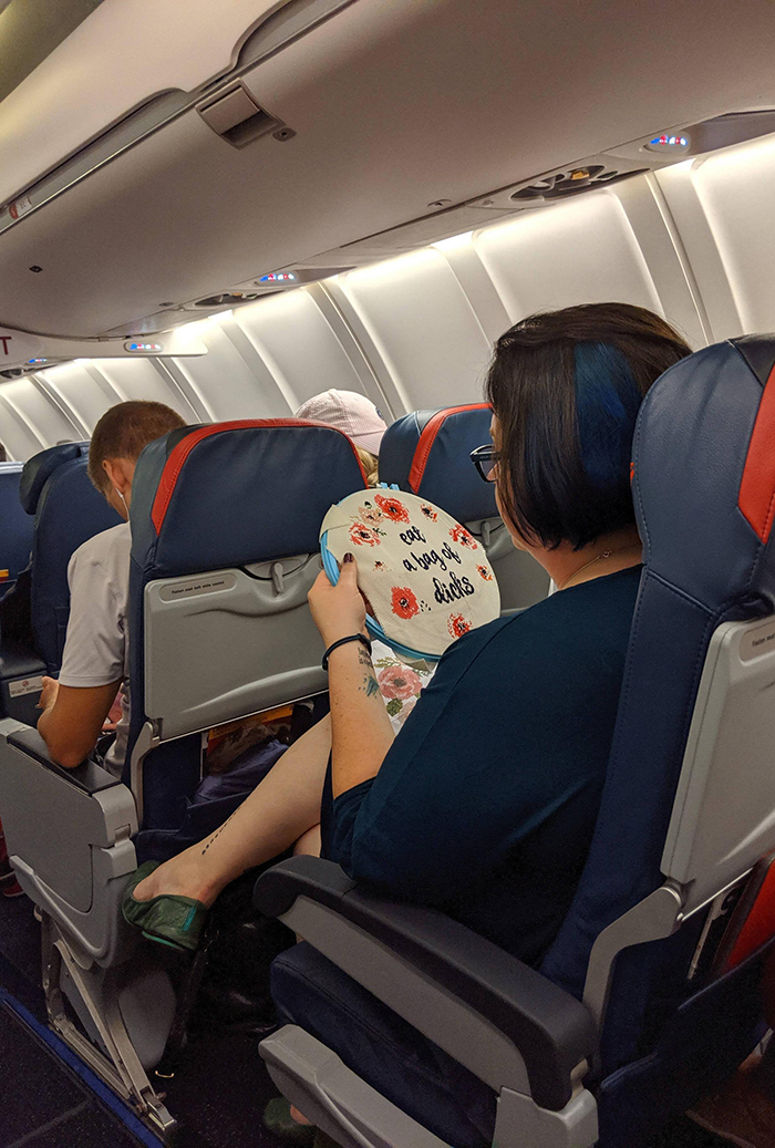 woman cross-stitching on plane