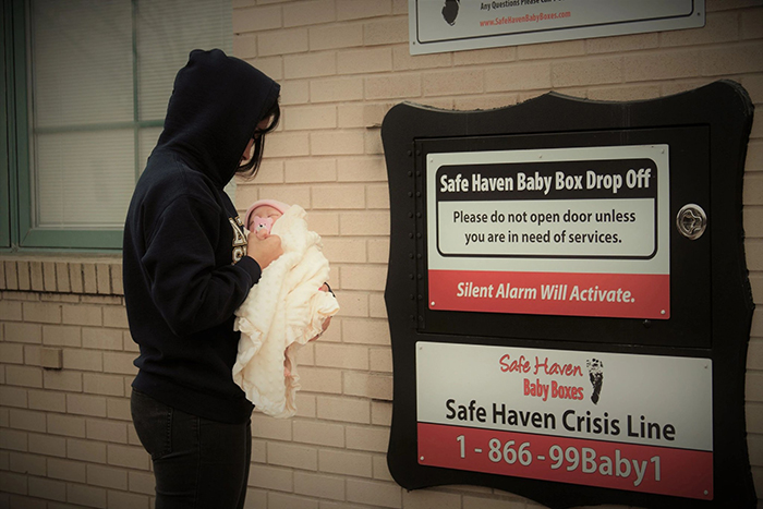 woman carrying a baby near a safe haven baby box